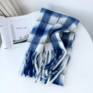Detailed view of checkered mohair scarf with fringes laid on a minimalist table
