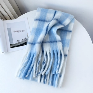Close-up of thick light blue plaid mohair scarf with soft fringes on a white table