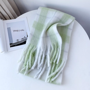 Detailed view of light green plaid mohair scarf with soft fringe on a white table