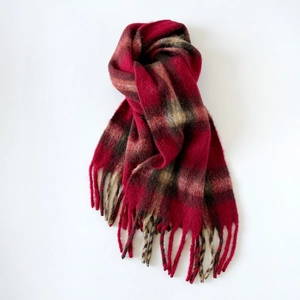 Detailed view of red plaid mohair scarf with soft brushed texture and fringe tassels