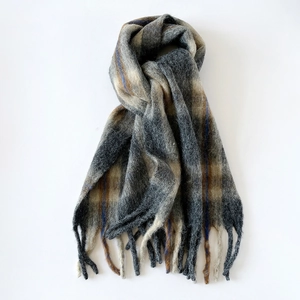 Detailed view of the thick wool scarf texture featuring a grey plaid pattern and fringes