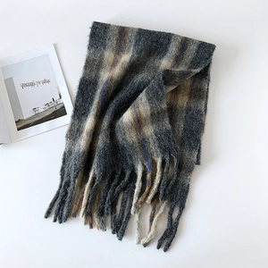 Detail of grey and beige checkered wool scarf with long tassels and soft plush texture
