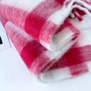 Close-up of fluffy red and white plaid mohair scarf texture with soft fringe details