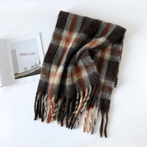Macro detail of thick mohair scarf with brown plaid pattern and soft long tassels