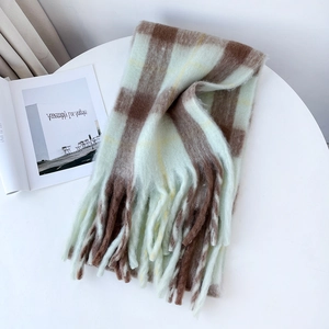 Close-up of thick mohair scarf featuring mint green plaid pattern and tassel fringe details