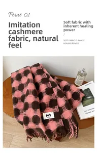 Close-up of pink and brown plaid faux cashmere scarf with fringe and 'M' logo tag