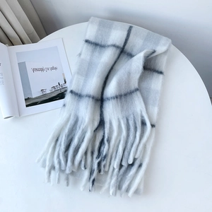 Detail of soft mohair-texture scarf featuring grey plaid pattern and fringe edges