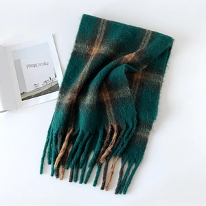 Macro detail of dark green and caramel plaid scarf with fringe and soft fuzzy texture