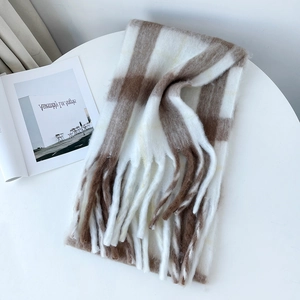 Detail of soft mohair-style plaid scarf with long fringes on a white minimalist table