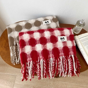 Close-up of checkered plaid scarves with fringe detail and branded woven label