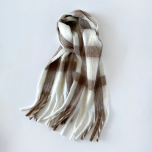 Detail of winter mohair scarf featuring brown plaid pattern and long tassel fringes