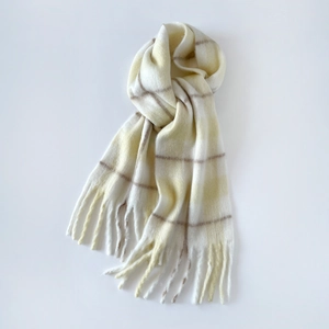 Close-up of soft plaid mohair scarf with tassels in cream, yellow, and brown tones