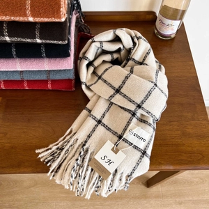 Detail of soft plaid scarf fringe and texture on a cozy winter wooden tabletop