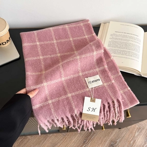 Detailed close-up of pink and white plaid scarf with soft fringe and stylish brand tag