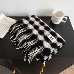 Detail of black and white checkered scarf with fringe and minimalist letter M label