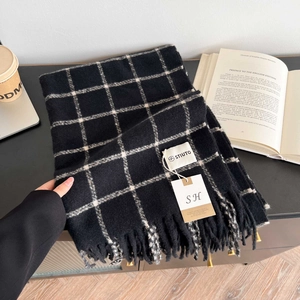 Detail of black and white plaid scarf featuring soft cashmere texture and fringe tassels