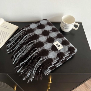 Detail of grey plaid cashmere-feel scarf with fringes and white woven brand label