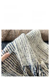 Detail of soft faux cashmere scarf featuring blue stripes and long fringe tassels