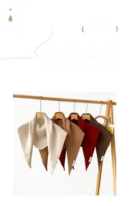 Detail view of knitted 100% wool triangle scarves in beige, khaki, red and brown