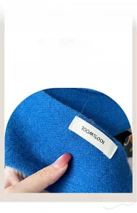 Detail view of the 100% pure wool label and fine knit texture of this royal blue shawl