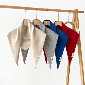 Detail of 100% wool knit triangle scarves in red, blue, grey and white on hangers