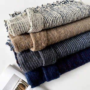 Close-up of stacked wool blend scarves showing fringe edges and thick knitted texture