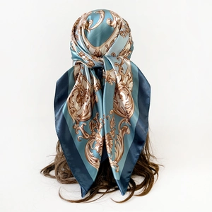 Detail of silk-like satin headscarf with golden Baroque patterns and a deep blue border