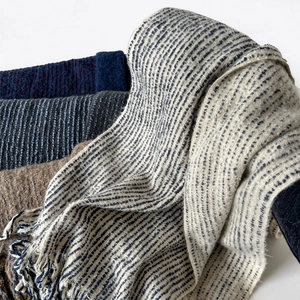 Close-up of soft striped knit scarves with fringe details in multiple winter colors