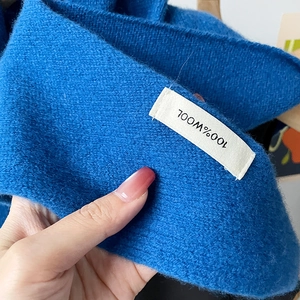 Macro shot showing 100% WOOL material label on navy blue knitted triangular scarf scarf