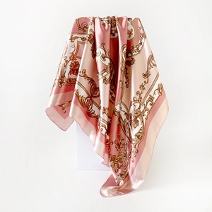 Close-up of pink satin square scarf with golden baroque pattern on white stage