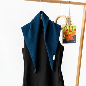 Detailed view of the 100% wool label on a dark blue knitted triangle scarf wrap