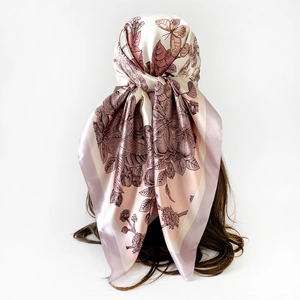Dettaglio di un foulard in seta con fiori e farfalle legato elegantemente sui capelli