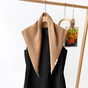 Macro detail of the 100% wool material label on a premium camel knitted triangle scarf