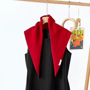 Detailed view of the 100% wool red triangle scarf with visible knitted texture on a hanger