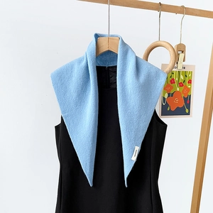 Detail view of a light blue 100% wool knitted triangle scarf draped on a black dress