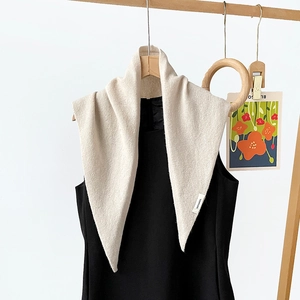 Detailed view of the 100% wool label on a minimalist cream knitted triangle shawl