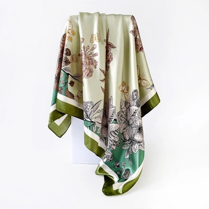 Dettaglio della sciarpa in raso con stampe di farfalle e motivi floreali su tessuto color champagne