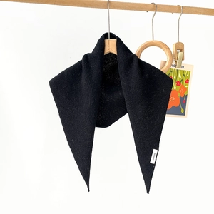 Detail showing 100% wool label and knit texture of a black triangular scarf shawl