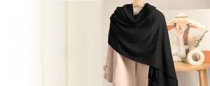 Detailed view of a black cashmere shawl with fringe tassels on a stylish wool coat