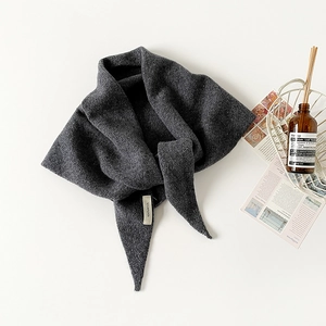 Close-up detail of the 100% wool wash label on a dark gray knitted triangle shawl scarf