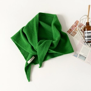 Detail shot of green 100% wool knitted triangle scarf with fine texture and soft drape