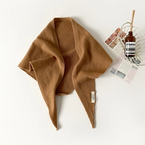 Detail of caramel knitted triangle scarf made of 100% wool showing fine texture
