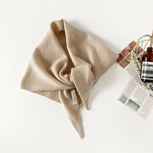 Detail of 100% wool knitted triangle scarf with visible texture and authentic wash label