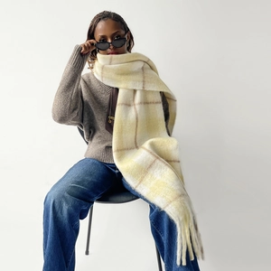 Close-up of thick checkered mohair scarf with cream, yellow and brown tones and long tassels