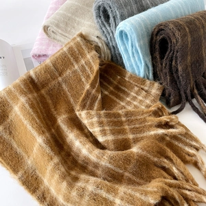 Macro shot of colorful plaid wool scarves with long tassels and soft mohair texture