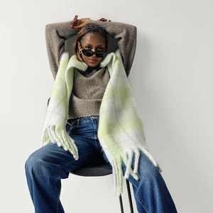 Detailed view of thick checkered mohair scarf with fringe trim and green-white pattern