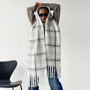 Detail shot of thick mohair scarf featuring large grey plaid patterns and long tassels