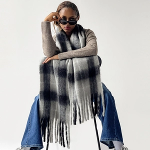 Detailed view of winter mohair scarf featuring black and white plaid with long tassels