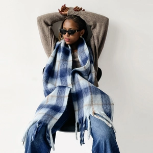 Detail of soft mohair scarf with blue and brown plaid patterns and fringe edges