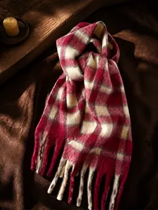 Gros plan sur l'écharpe en mohair à carreaux rouge et beige avec d'épaisses franges
